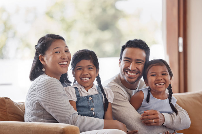 Happy young family of four sitting on couch